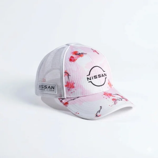 Gorra publicitaria tipo trucker de Nissan Formula E Team, color rosa pastel con diseño de flores de cerezo (Sakura), malla blanca, parche lateral y logotipo central.